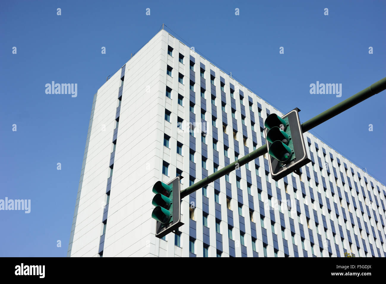 Weißes Gebäude mit einer grünen Ampel in den Vordergrund und blauer Himmel Stockfoto