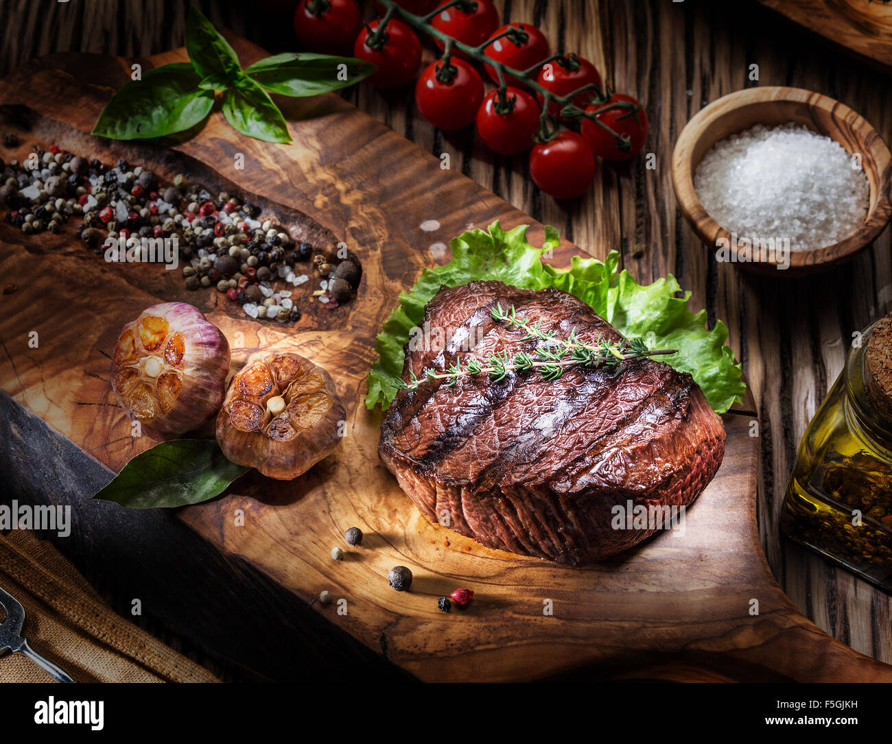 Rindersteaks mit Gewürzen auf einem Holztablett. Gegrillte Speisen. Stockfoto