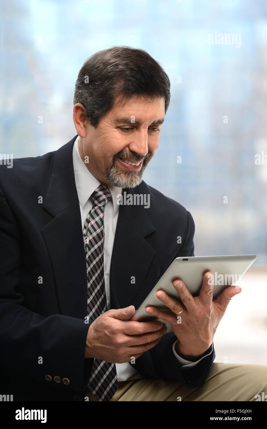 Porträt von Hispanic Geschäftsmann mit elektronischen Tablet in der Nähe von Bürofenster Stockfoto