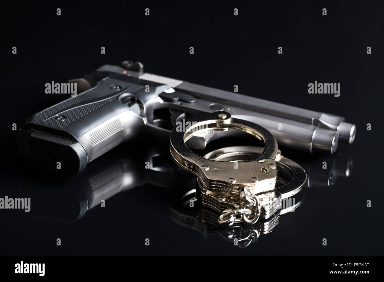Handschellen und Pistole auf schwarzem Hintergrund Stockfoto