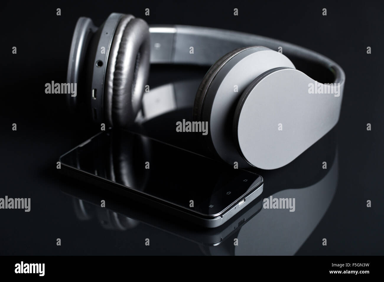 Kopfhörer und Smartphone auf schwarzem Hintergrund Stockfoto