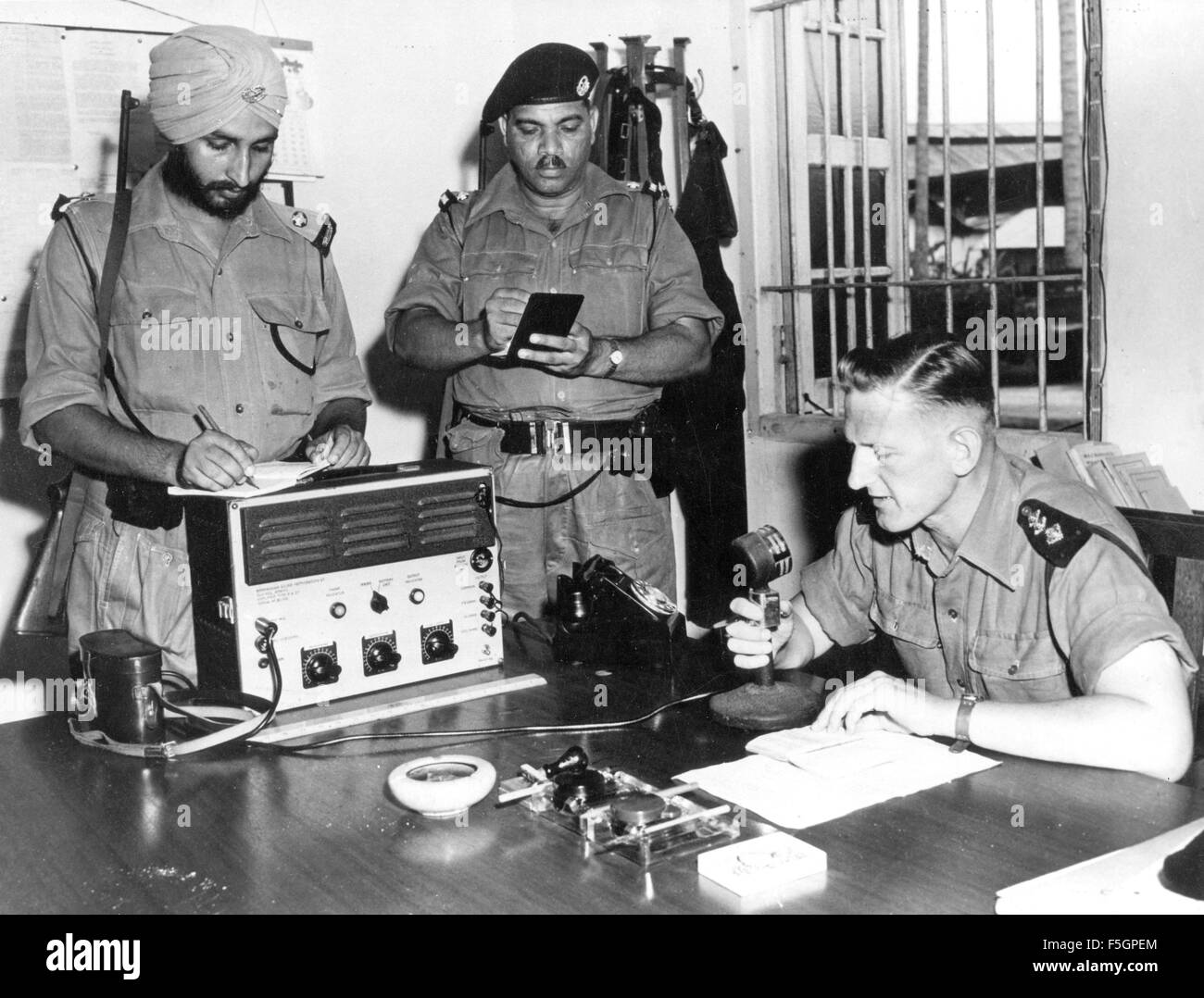 MALAYAN EMERGENCY 1948-1960. Officer Commanding Kuala Lumpur Dschungel Kader, John Gladwell, macht eine Ankündigung vom Kontrollraum mit Inspektor Alma Singh auf der linken Seite und Sub-Inspector Rustan Ali, ca. 1958 Stockfoto