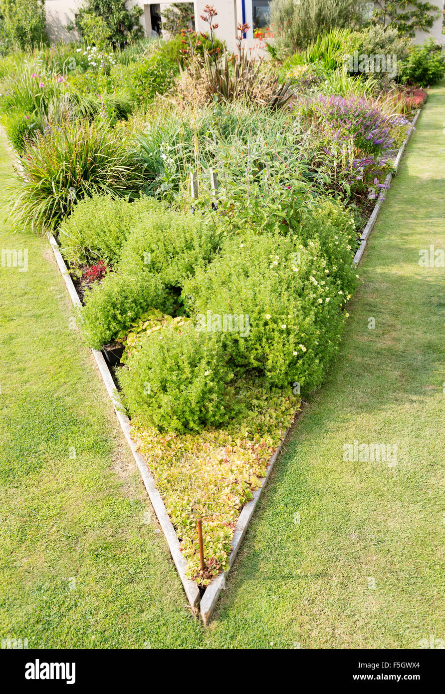 Dreieckige erhöhten Blumenbeet auf der großen Wiese im Garten. Stockfoto