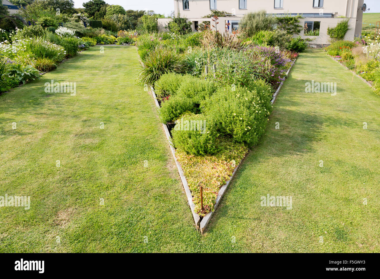 Dreieckige erhöhten Blumenbeet auf der großen Wiese im Garten. Stockfoto