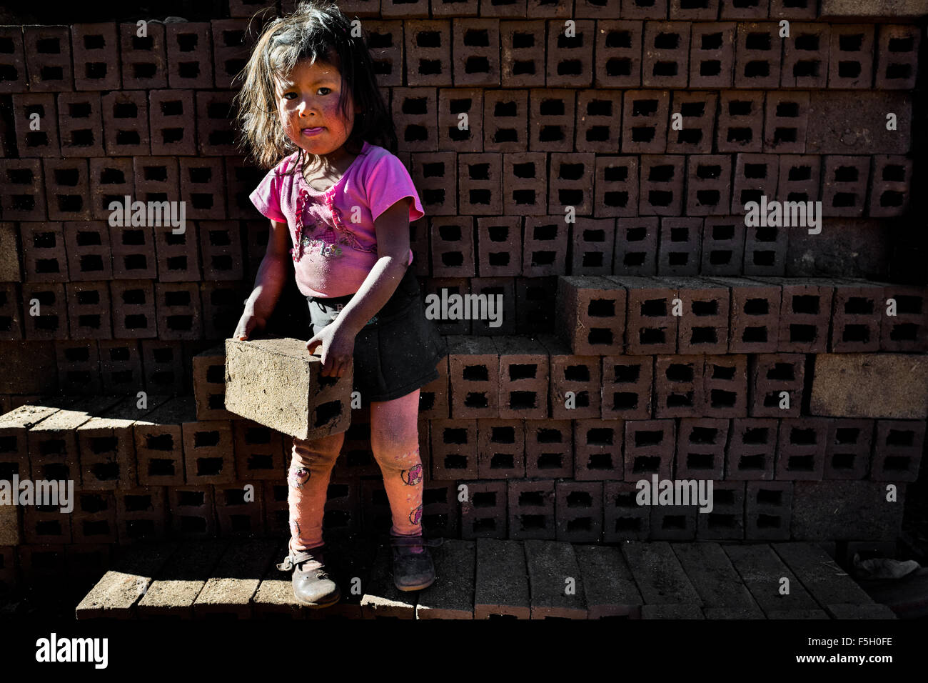 Eine 5-Jahr-alten peruanischen Mädchen trägt Ziegel auf eine Ziegelei in der Nähe von Puno, Peru. Stockfoto