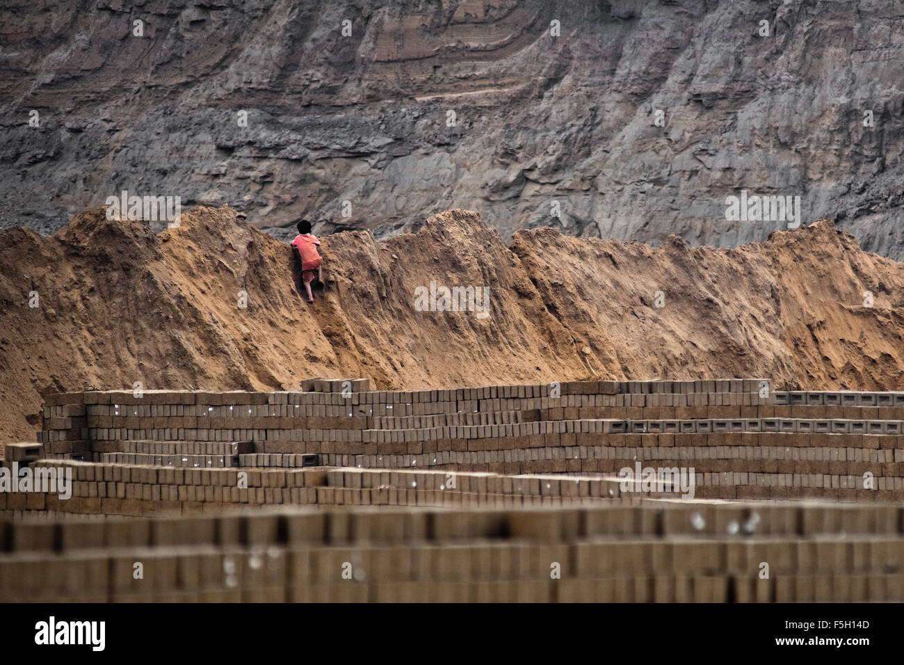 Ein peruanischer Junge klettert den Haufen von Schlamm während der Arbeit an einer Ziegelei in Huachipa, einem Vorort in der Nähe von Lima, Peru. Stockfoto