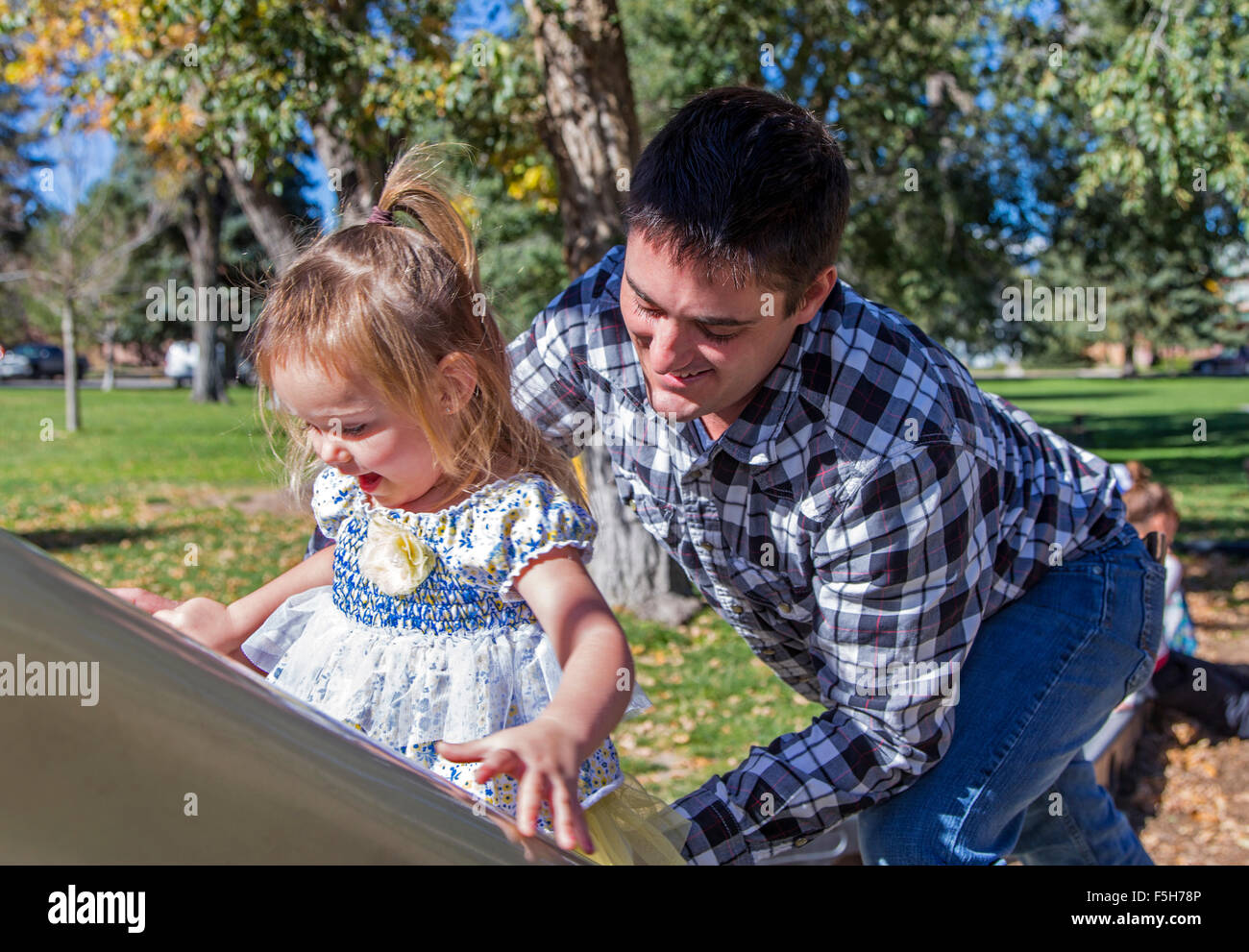 Vater und junge Tochter spielt auf einem verschiebbaren Brett, Park Spielplatz Stockfoto