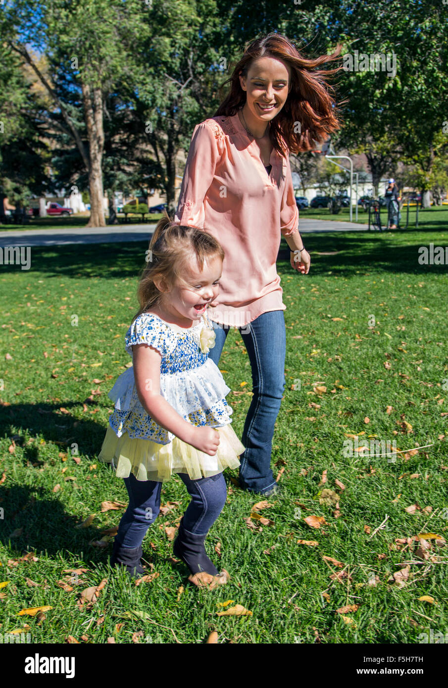 Schöne Mutter spielen auf Rasen mit niedlichen kleinen Tochter, Stadtpark Stockfoto