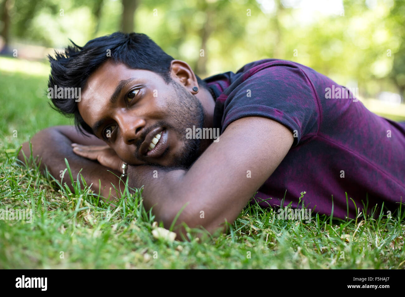 ein junger Mann liegt auf dem Rasen im park Stockfoto