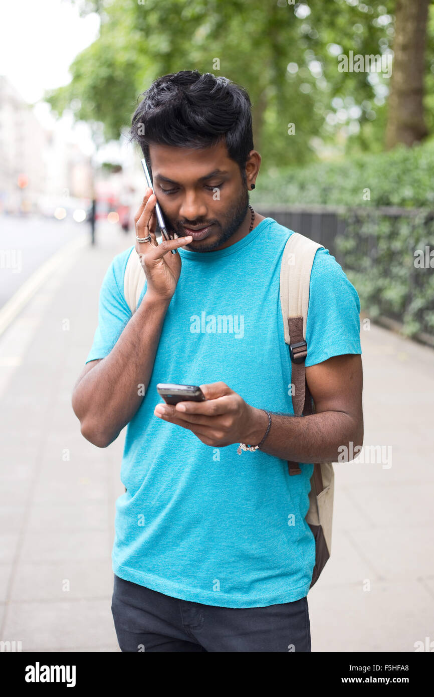 junger Mann mit zwei Telefonen anrufen Stockfoto