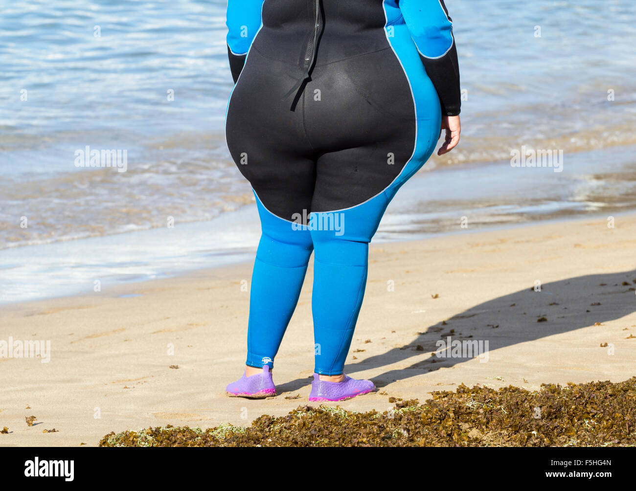 Übergewichtige Frau trägt Neoprenanzug Ar Wassersportzentrum am Strand in Spanien Stockfoto