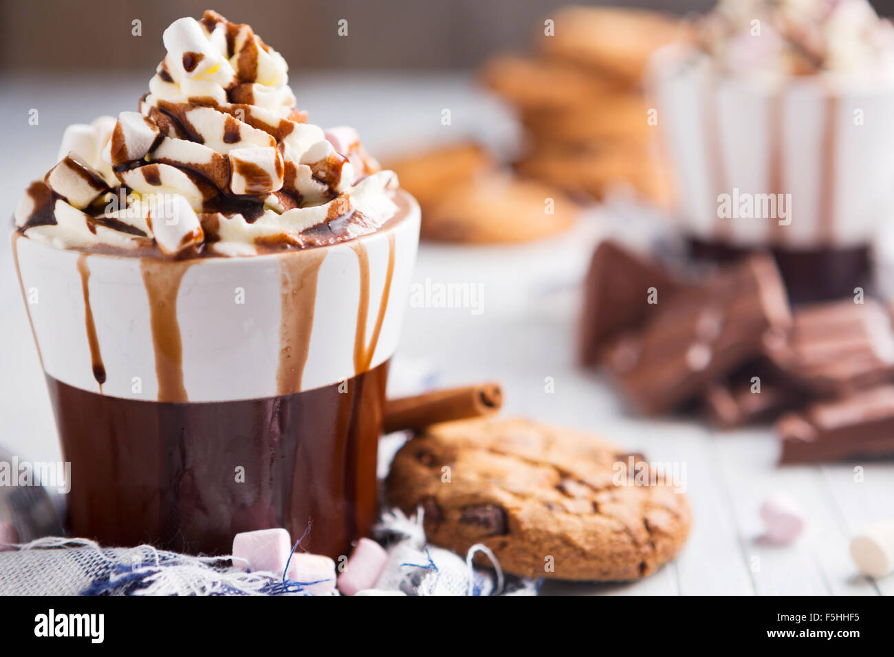 Eine unordentliche Tasse mit heißer Schokolade, Sahne, Marshmallows und Choclate Chip Cookies. Stockfoto