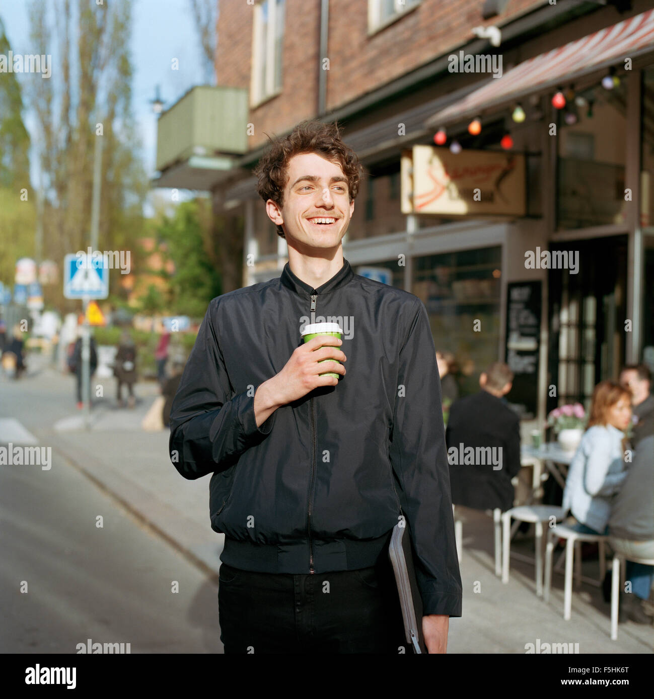 Schweden, Stockholm, Sodermalm, Nytorget, lächelnd Mann stand auf der Straße mit Laptop und Einweg-Becher in der hand Stockfoto
