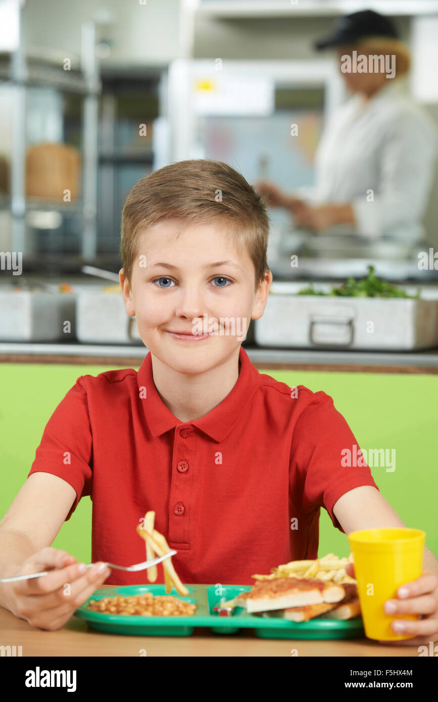 Männliche Schüler sitzen am Tisch In der Schulcafeteria ungesundes Essen Stockfoto