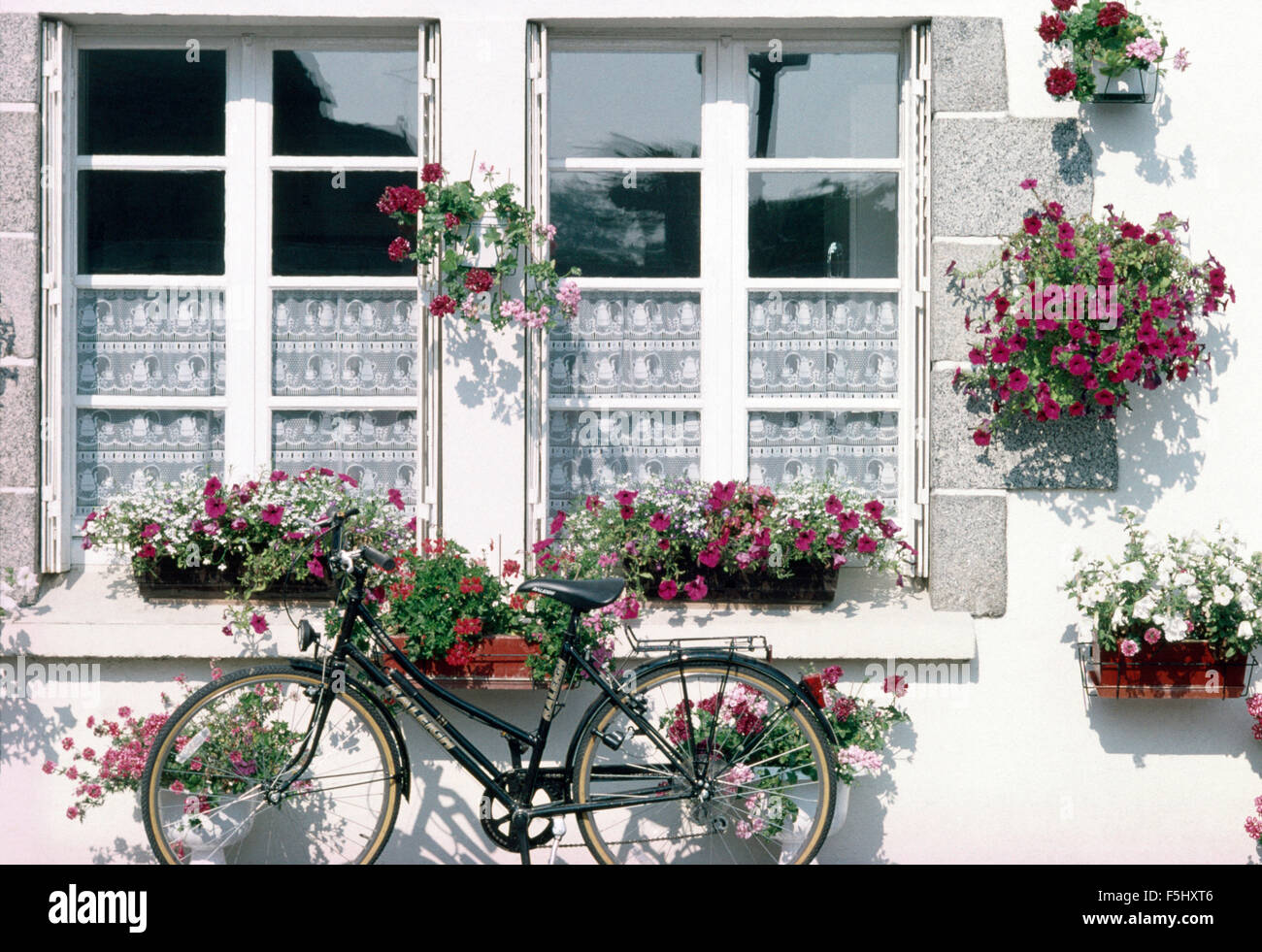 Fahrrad gelehnt französische Haus mit bunten Sommerblumen in Balkonkästen und Ampeln Stockfoto