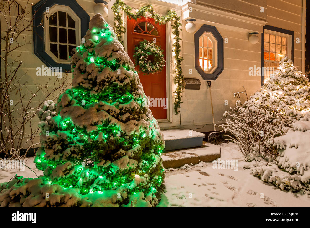 Ein Haus verziert mit Kranz, Kranz und Weihnachten Lichter ein einer klaren Winternacht. Stockfoto