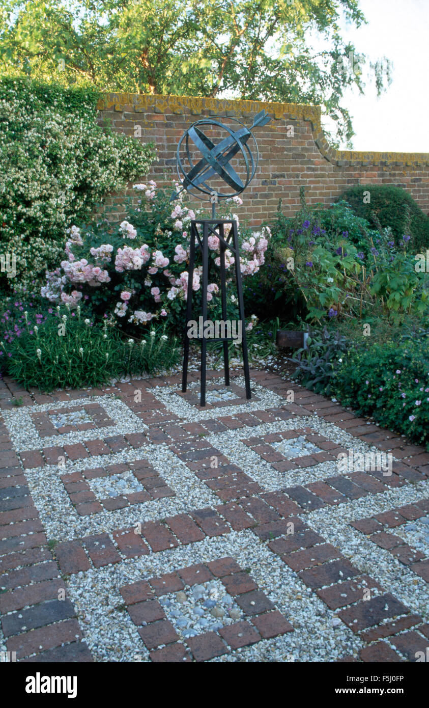Große Version am Stand auf Ziegel + Kies Pflaster in einem ummauerten Garten mit rosa Rosen in einer Grenze Stockfoto
