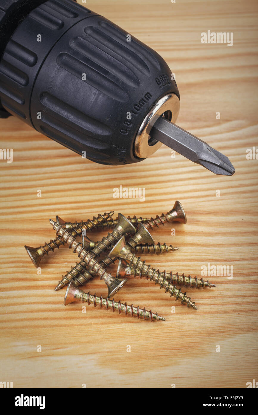 Akku-Bohrschrauber und großen Schrauben auf Holz Hintergrund Stockfoto