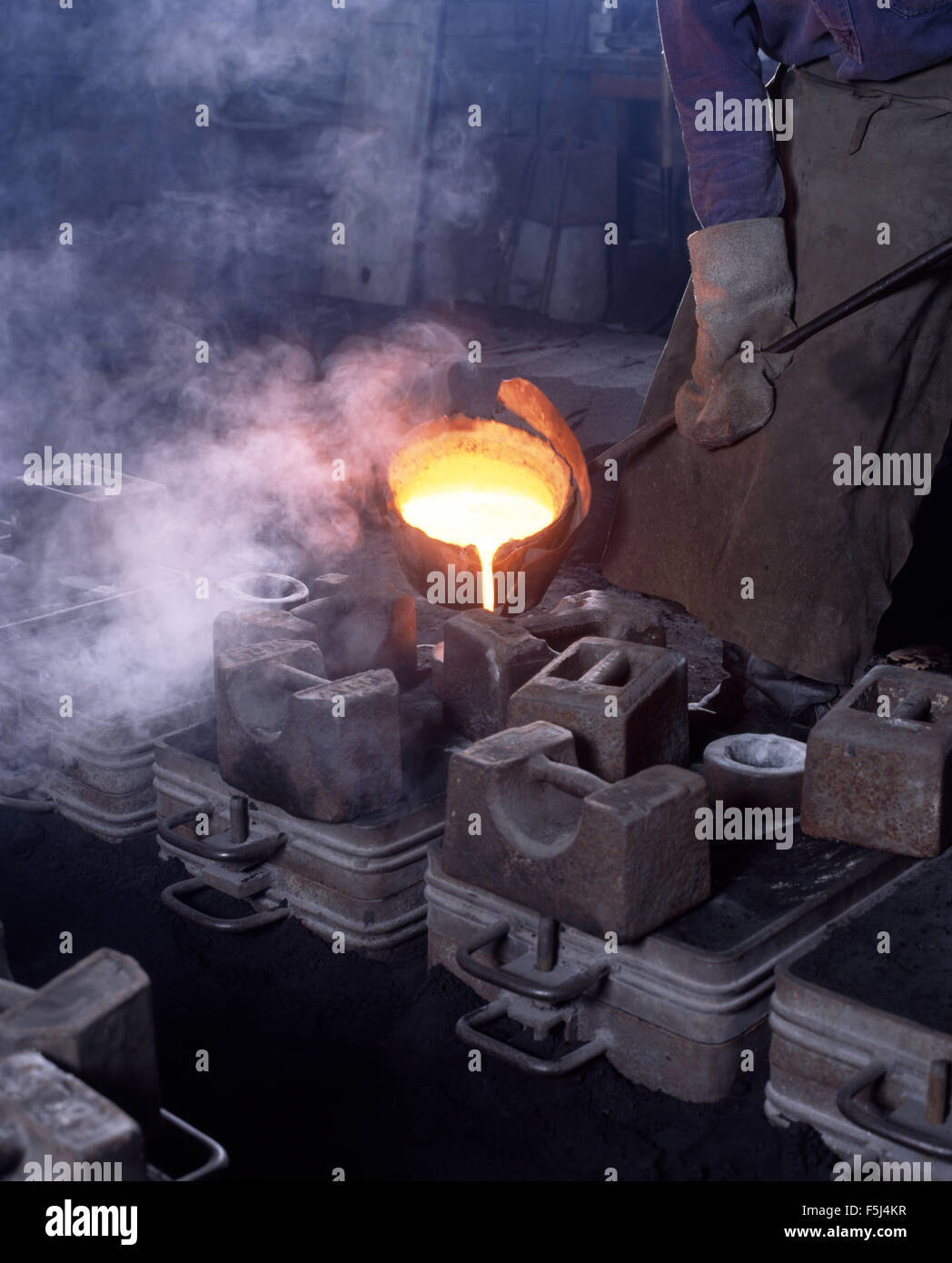 Handwerker, gießt geschmolzenes Eisen in Formen in einer Eisengießerei Stockfoto
