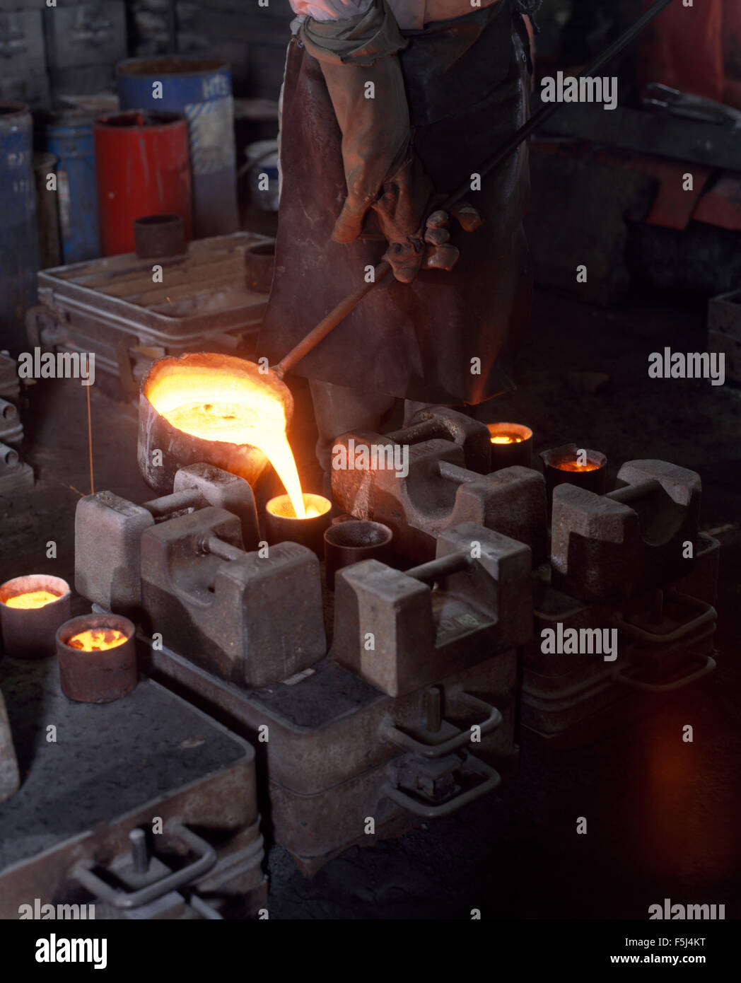 Nahaufnahme eines Handwerkers Gießen geschmolzenes Eisen in eine Urne in eine Eisengießerei Stockfoto