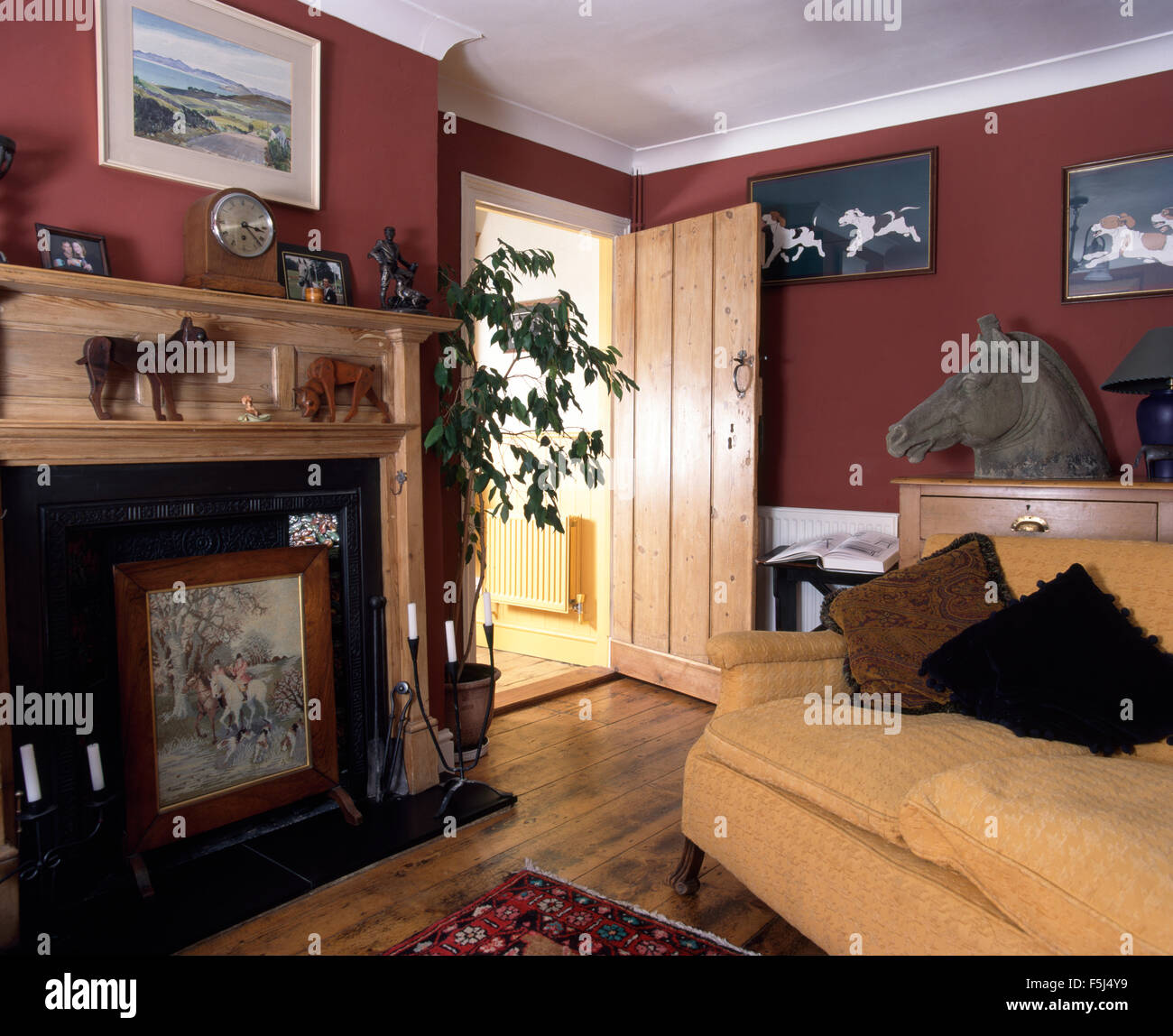 Kiefer Kaminsims über dem Kamin mit FUNKENSCHUTZGITTER in einer dunklen roten neunziger Jahre Wohnzimmer Stockfoto