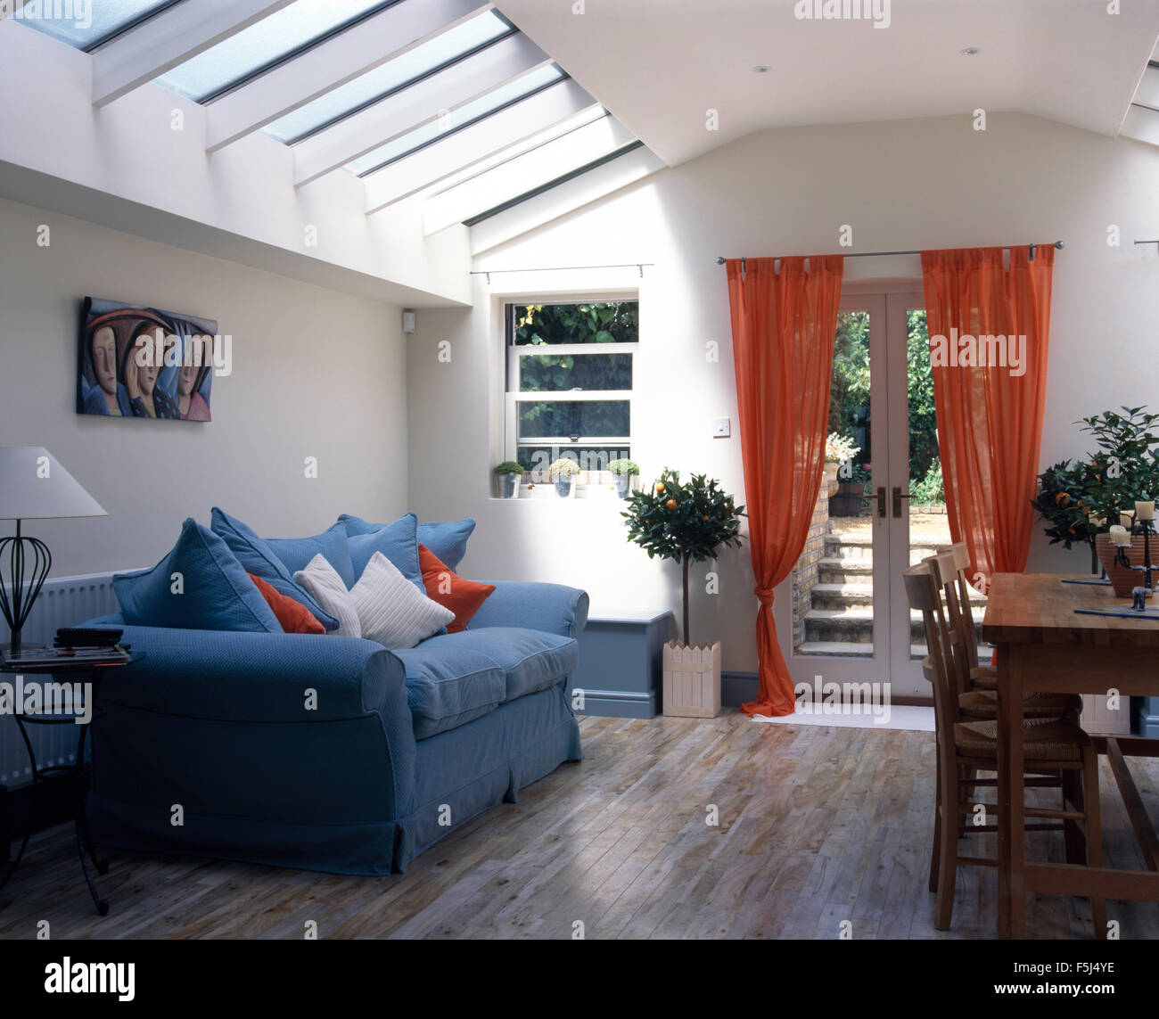 Blaues Sofa und Orange Voile Vorhänge in Wohn- und Esszimmer-Erweiterung  mit Holzboden Stockfotografie - Alamy
