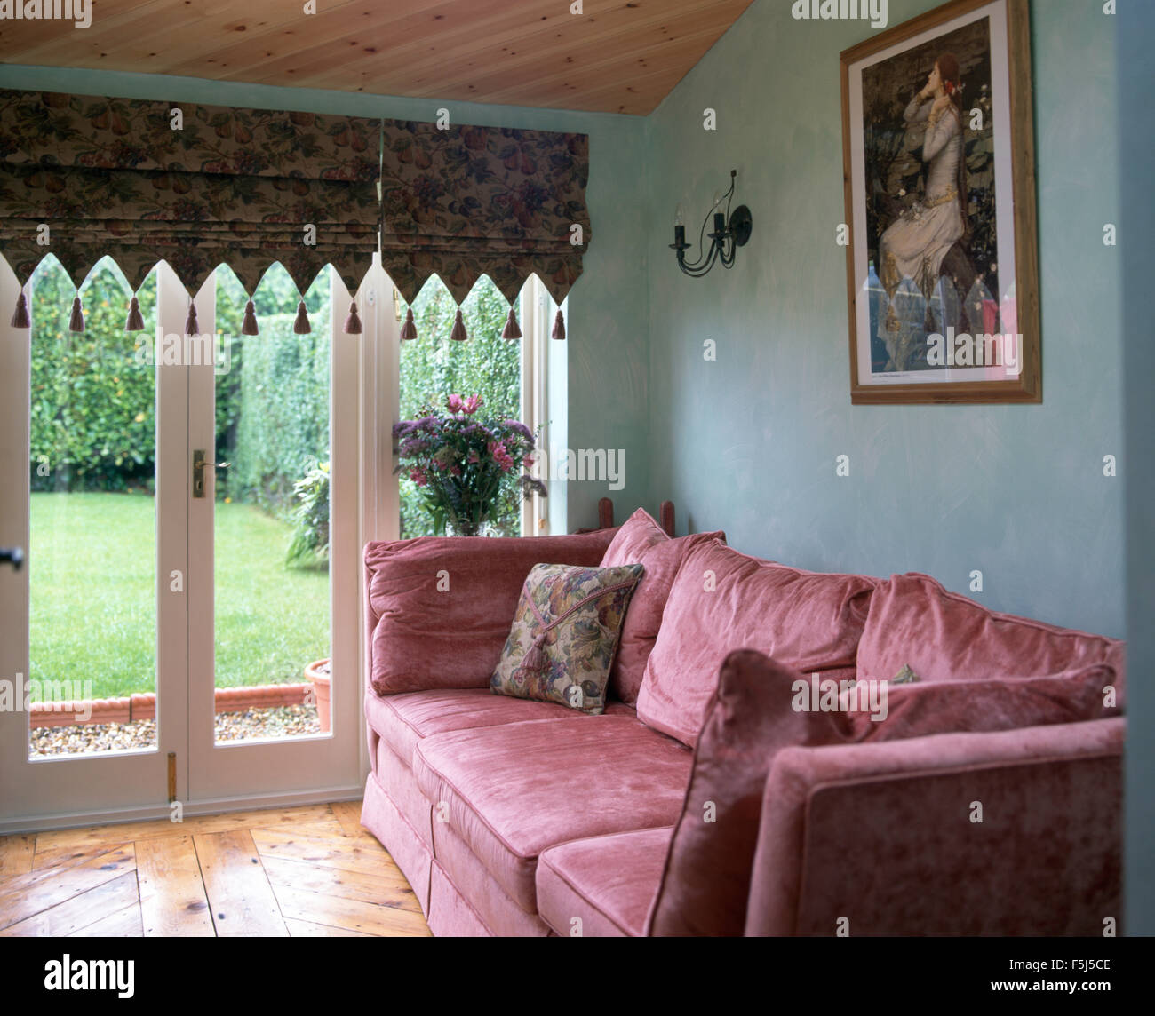 Rosa samt Sofa in einer blauen neunziger Jahre Wohnzimmer mit einem  tasseled Faltrollo auf Glas Terrassentüren Stockfotografie - Alamy