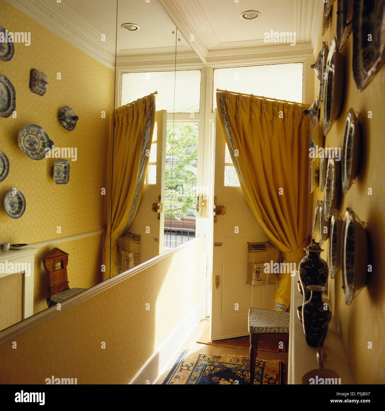 Spiegelwand in ein gelbes achtziger Jahre Halle mit einem gelben Vorhang an der Eingangstür Stockfoto