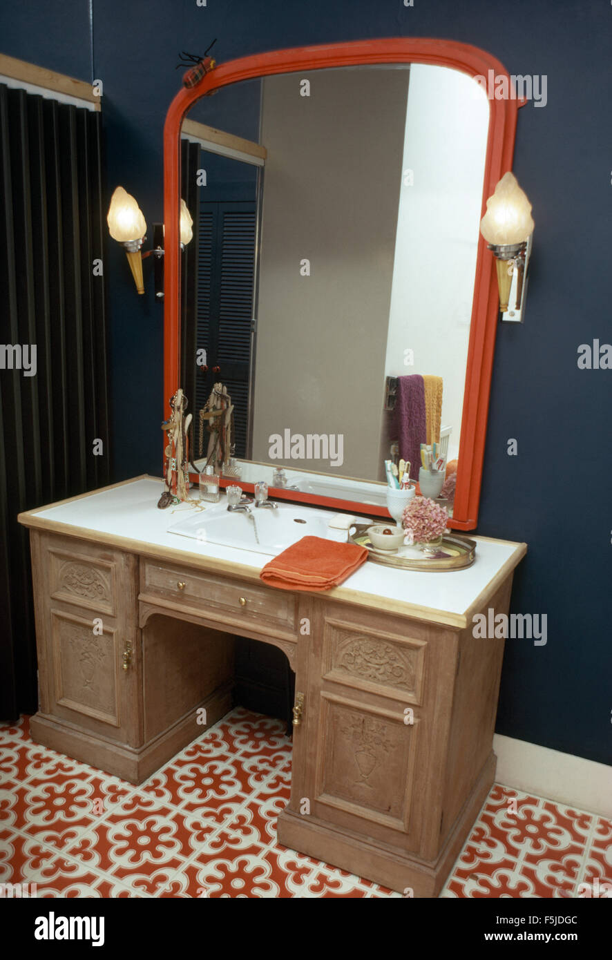 Rot bemalte Spiegel über dem Waschbecken gesetzt in einem Vintage  Schreibtisch in einem 60er Jahre Bad Stockfotografie - Alamy