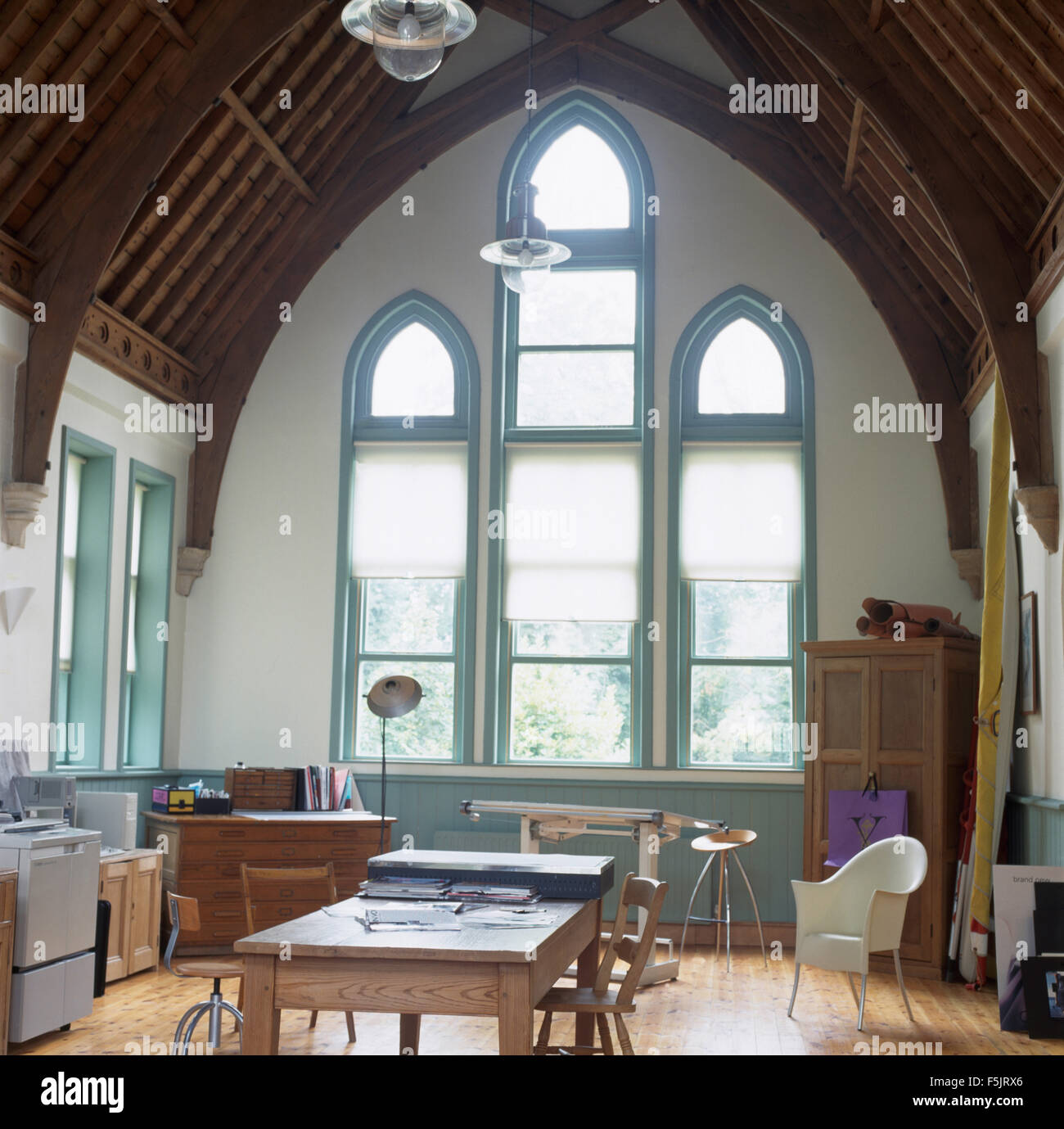 Weiße Vorhänge auf hohe gotische Fenster in einem großen Studio-Speisesaal in einer umgebauten Kapelle Stockfoto