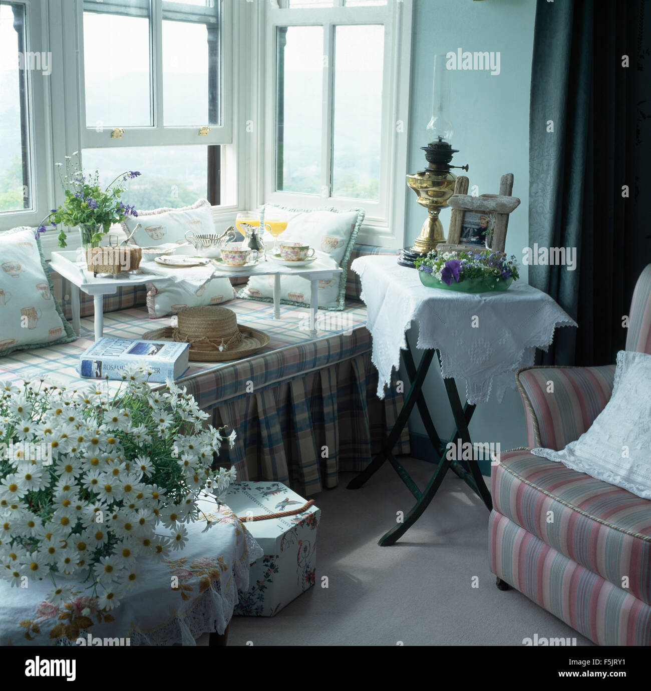 Frühstückstablett auf Fensterplatz in einem Land-Schlafzimmer mit einer Vase mit weißen Margeriten auf Tisch Stockfoto