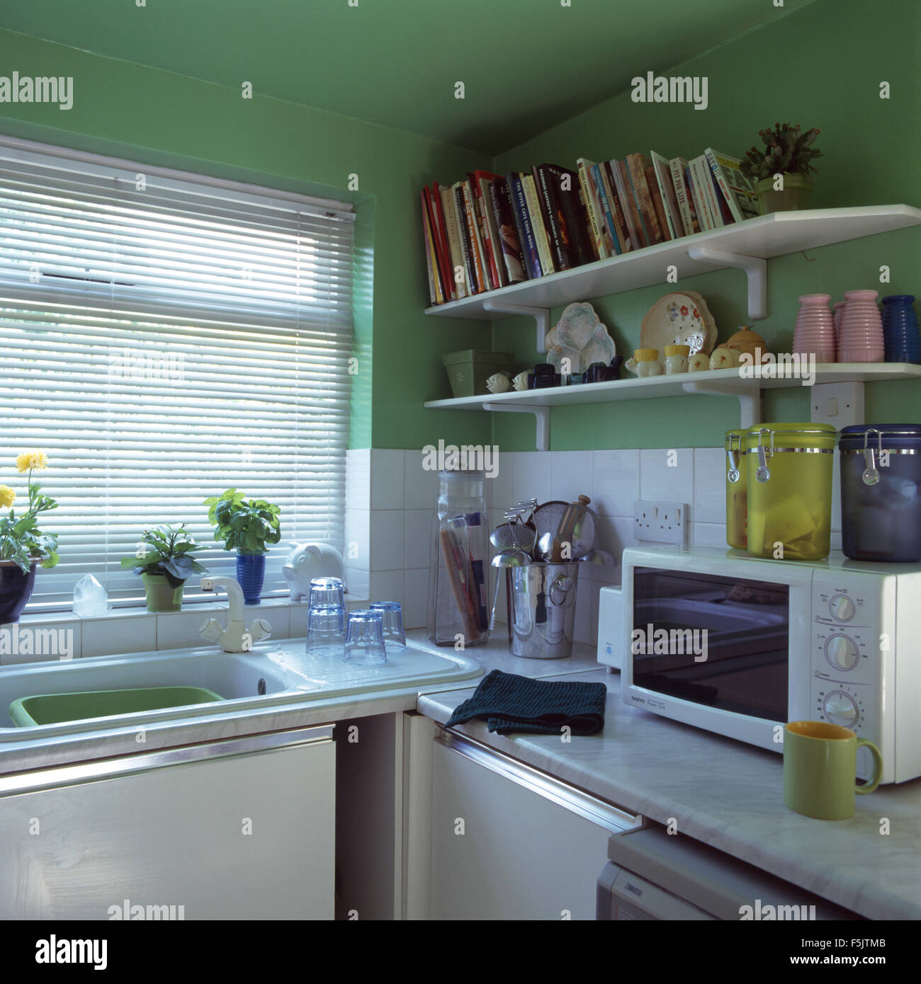 Offenen Regalen oberhalb Arbeitsplatte mit Mikrowelle in einer grünen Wirtschaft Stil der 90er Jahre Küche Stockfoto