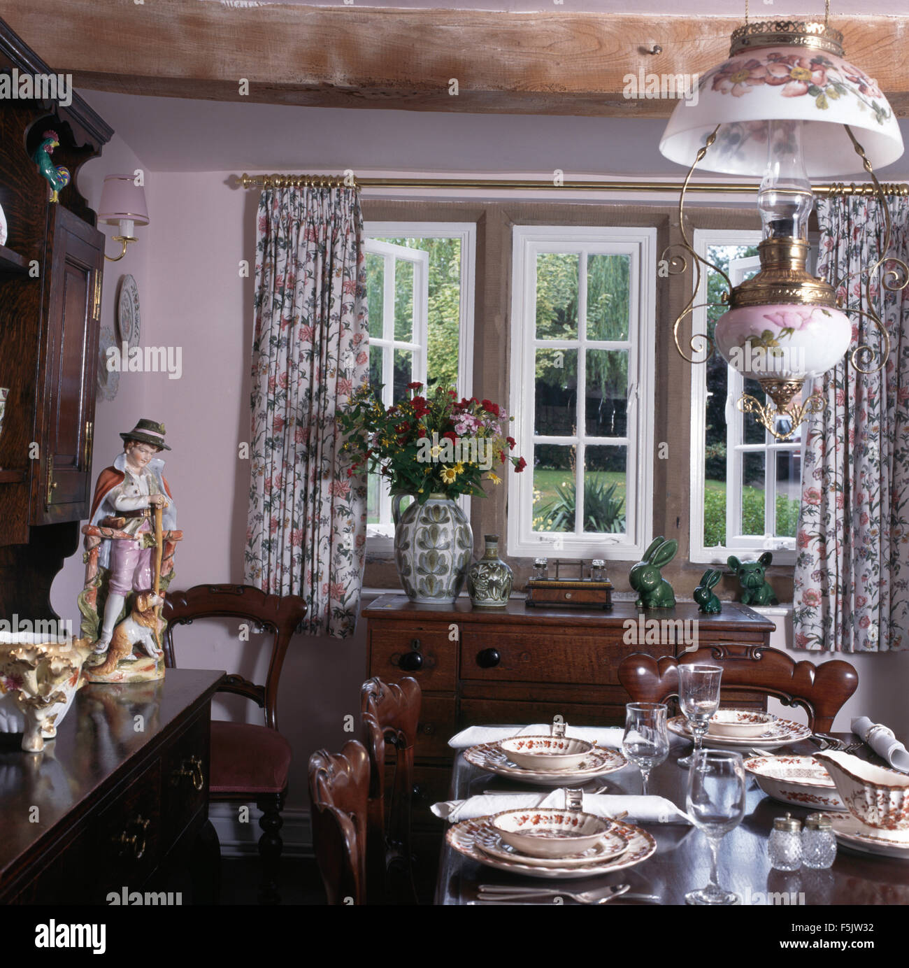 Tabelle Gruppe zum Mittagessen in der neunziger Jahre Cottage Esszimmer mit einer floralen viktorianischen Stil Messing und China Pendelleuchte Stockfoto