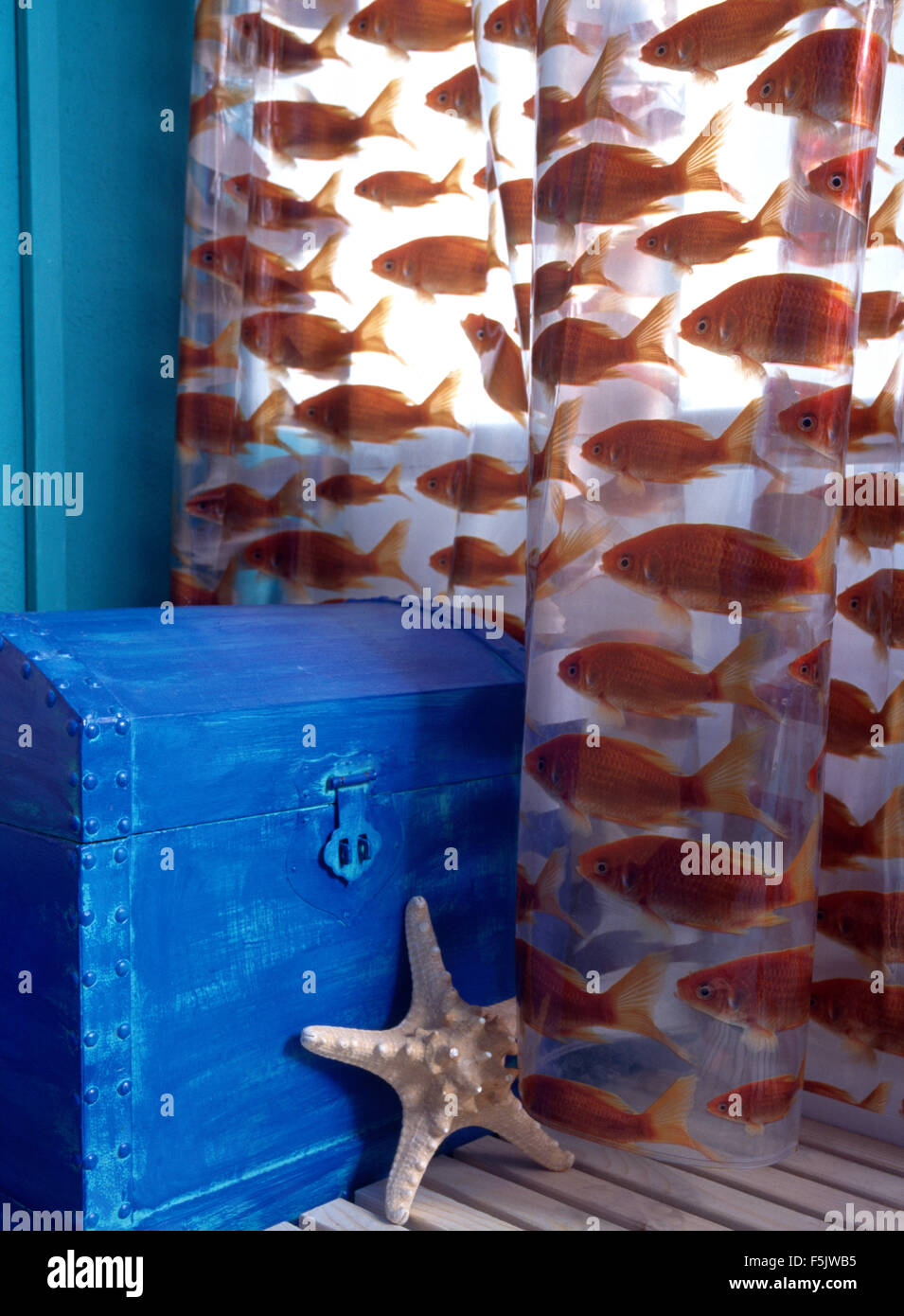 Nahaufnahme von einen kleinen blau bemalten Schrank und Fisch gemusterten Kunststoff Duschvorhang Stockfoto
