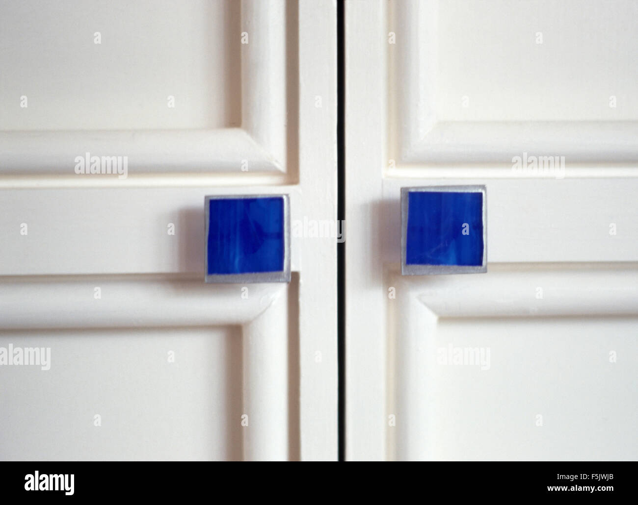 Nahaufnahme des weißen Schrank mit quadratischen blauen Griffen Stockfoto