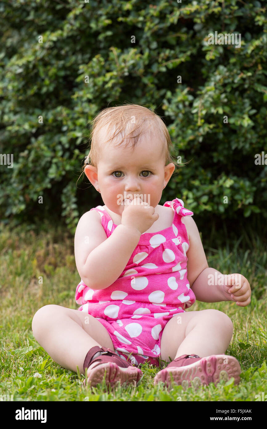 Glücklich niedliche kleine einjährige Mädchen im Freien, Sommer, mit rosa Kleid Stockfoto