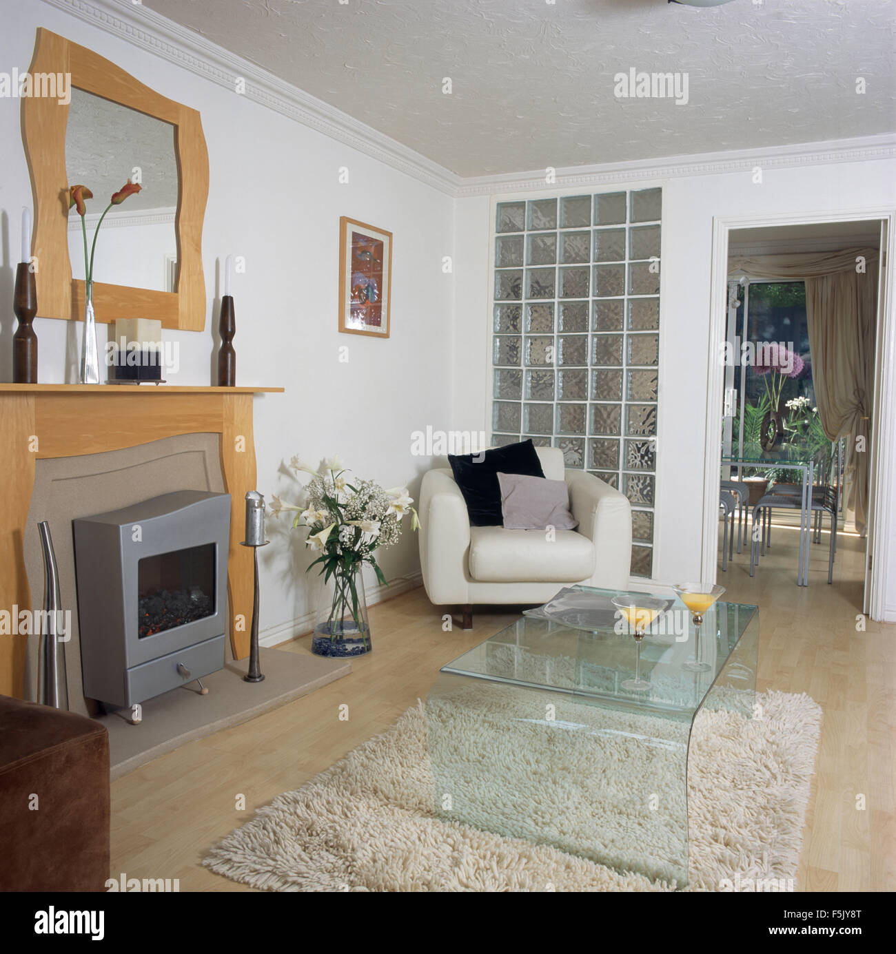 Acryl Couchtisch auf Shag Teppich in ein Wohnzimmer mit einem Metall Gasfeuer und Glaswand neben der Tür der neunziger Jahre Haufen Stockfoto