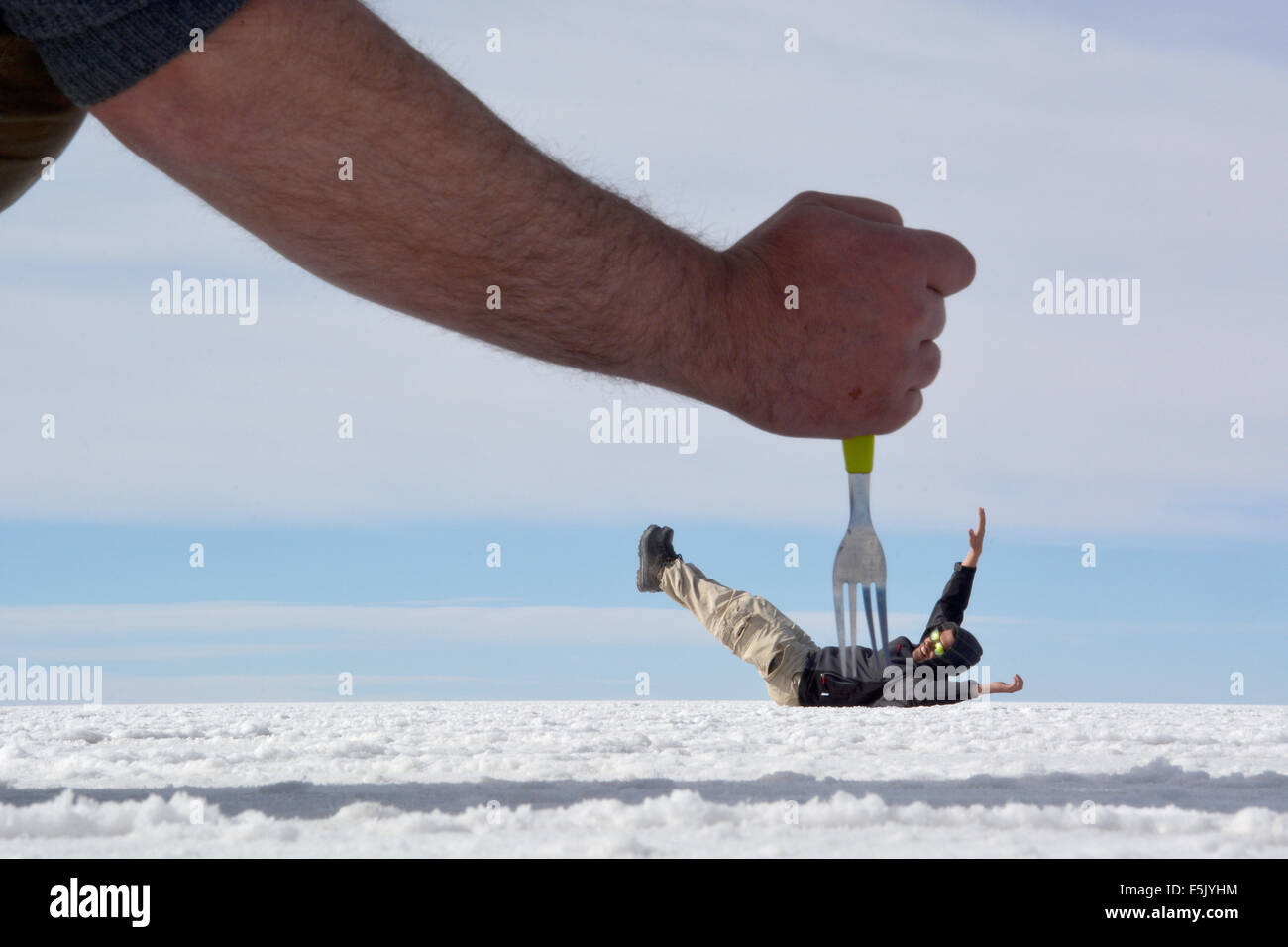 Optische Täuschung, Mann wird erstochen, mit einer Gabel, Salar de Uyuni, Bolivien Stockfoto