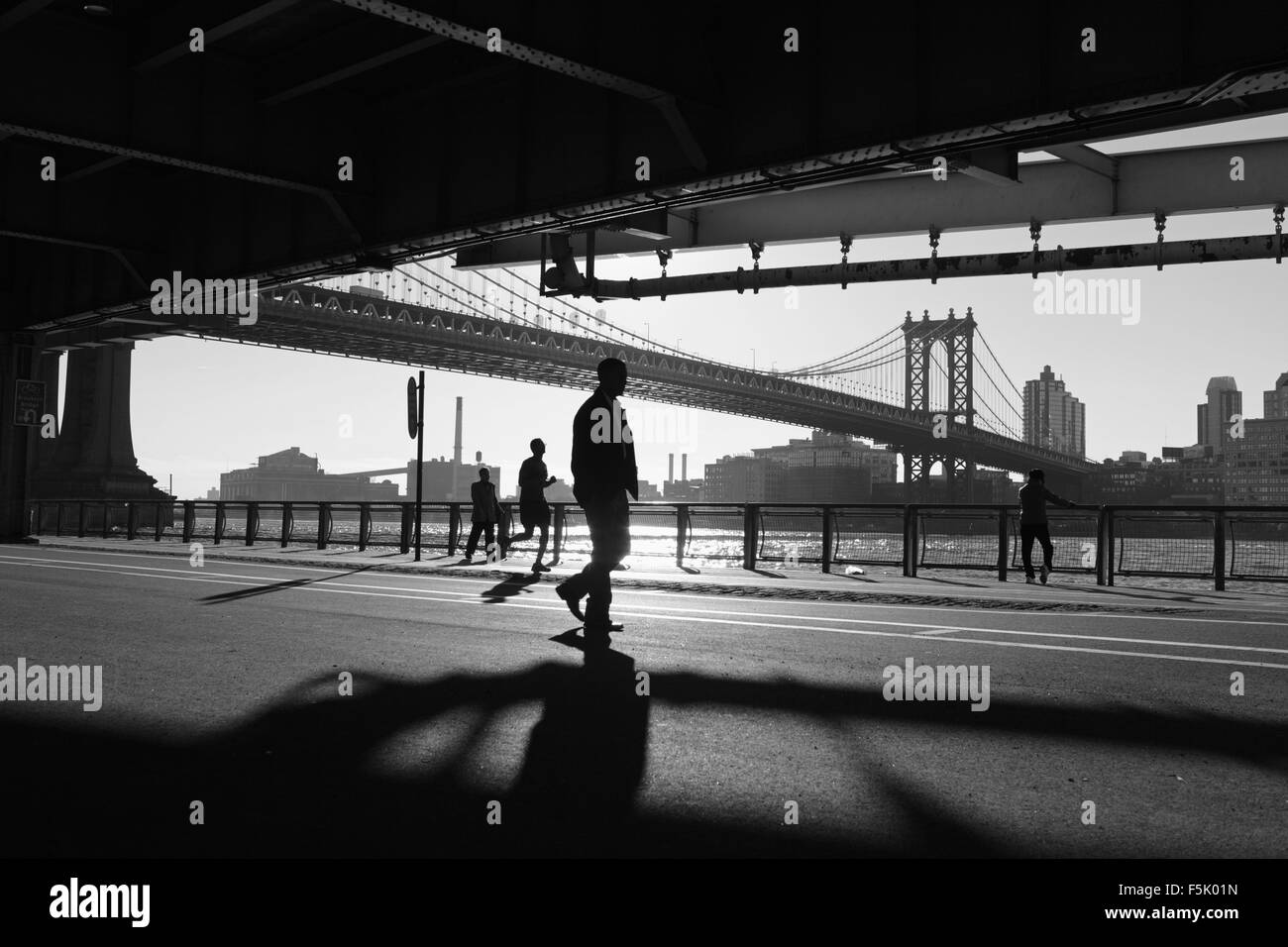 Zwei Chinatown Frauen ausüben, läuft ein Mann, ein anderer Mann geht beim betrachten die anderen entlang des East River Esplanade, New York Stockfoto