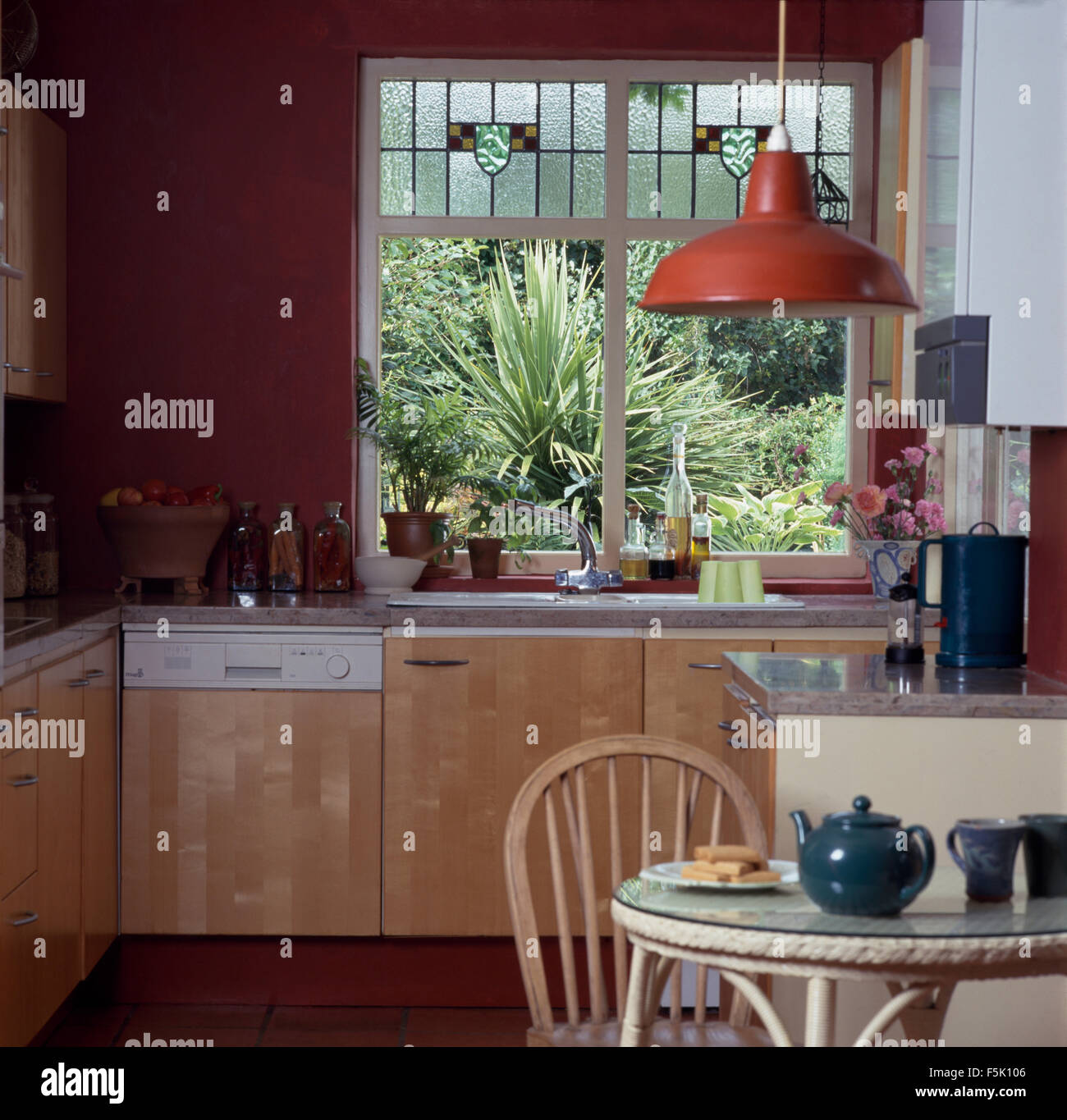 Stained Glass Panels im Fenster über der Spüle und Geschirrspüler in der Küche mit roten Emaille Gewicht der Leuchte Stockfoto