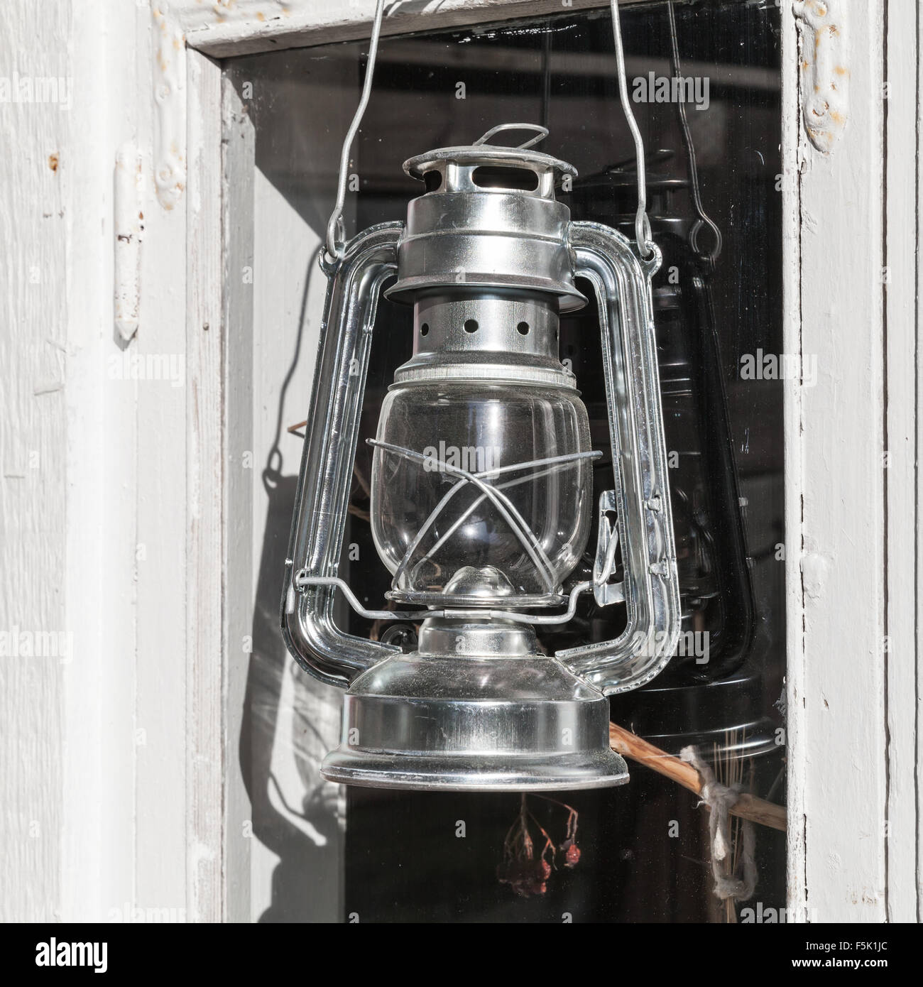 Glänzende Metall Petroleumlampe hängt an weißen Holzrahmen in Finnland Stockfoto