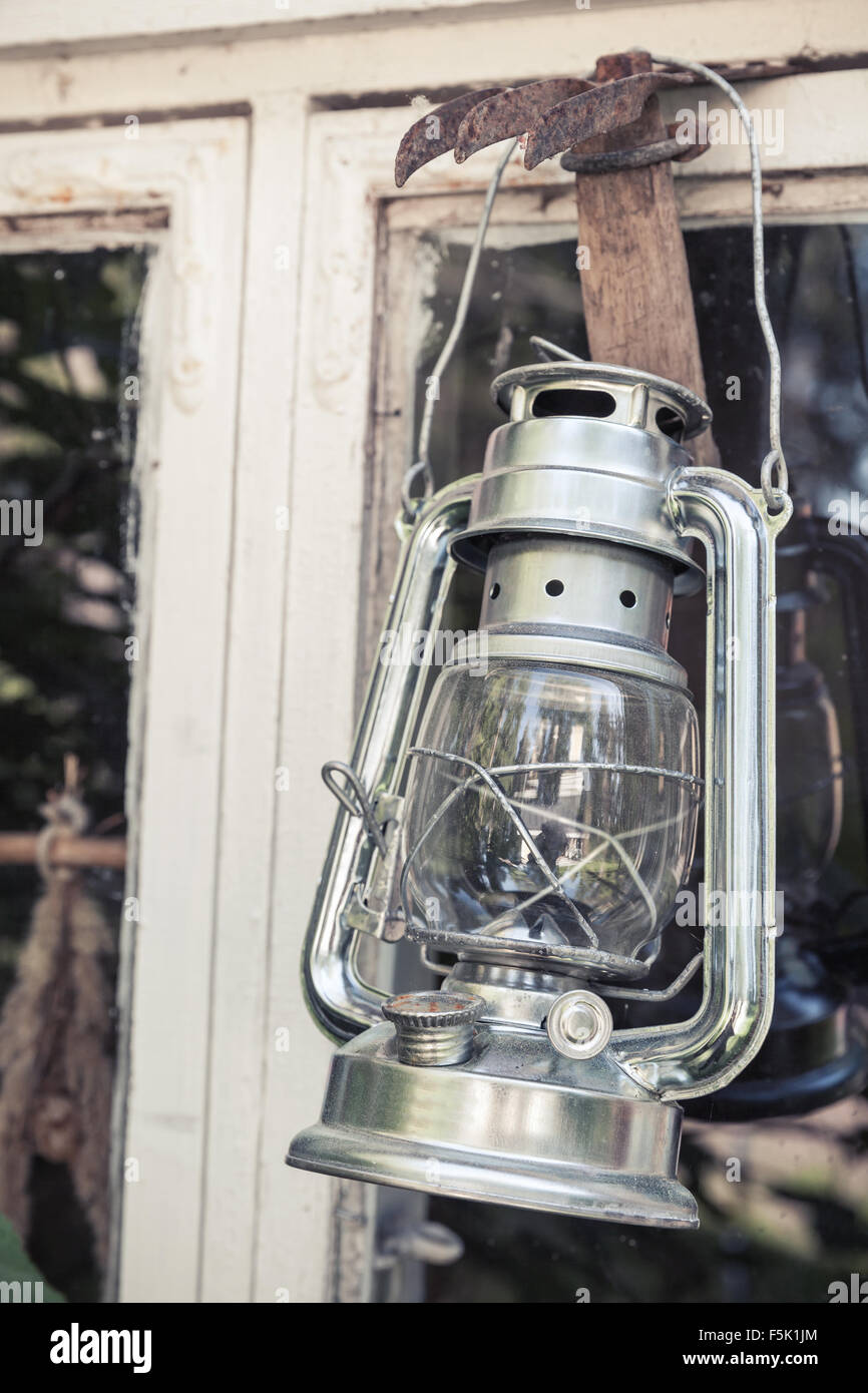 Glänzende Metall Kerosin-Lampe hängt auf weißen Holzrahmen in Finnland, getönten Vintage Foto mit alten Stil Filterwirkung Stockfoto