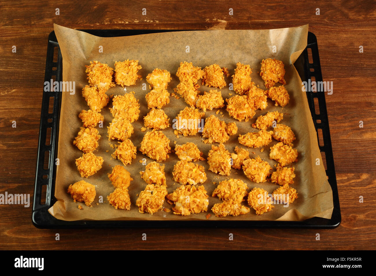 Frisch gebackenes Hühnerfilet auf Backblech legen. Ofen gebacken Mais  Flocken Krümel Hähnchen-Nuggets. Serie Stockfotografie - Alamy