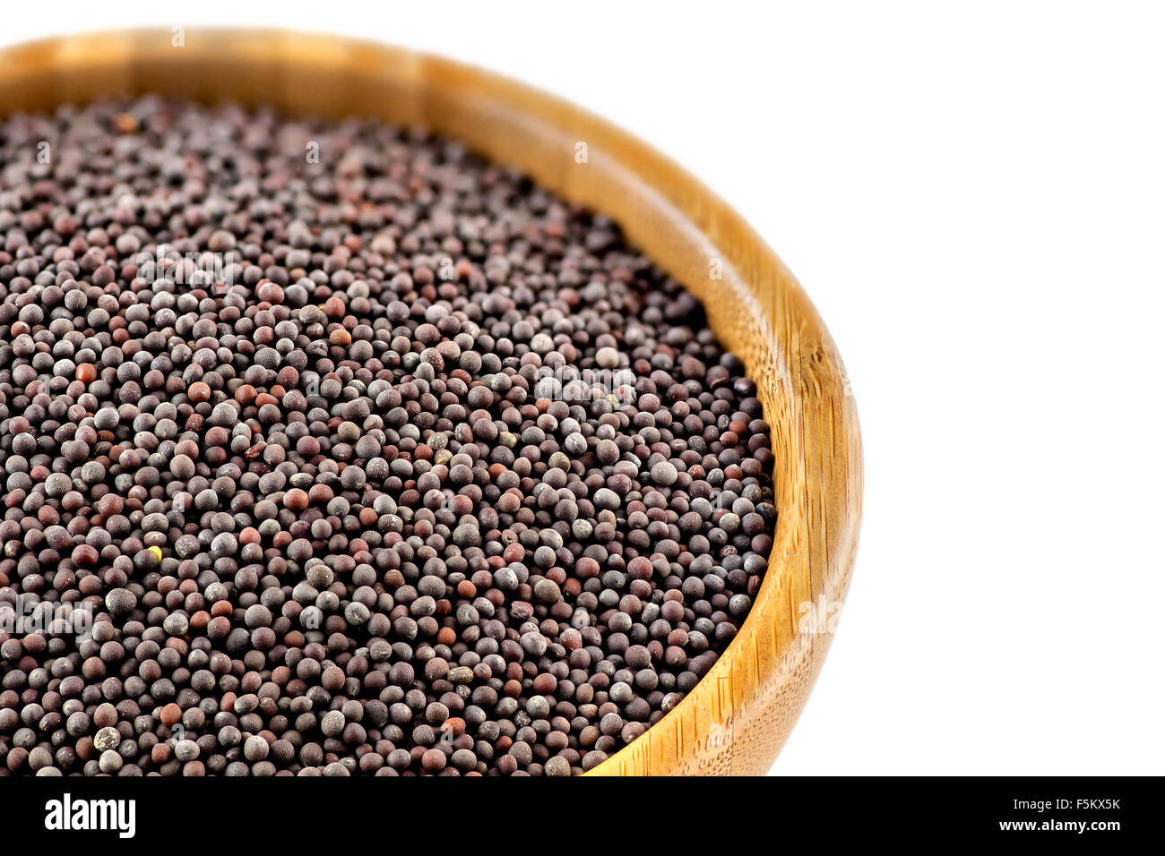 Closeup Schuss schwarze Senfsamen in einer rustikalen Holzschale auf weißen Hintergrund isoliert. Stockfoto
