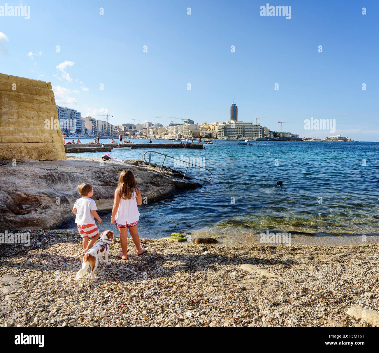 Kinder, Junge und Mädchen mit Hund am Strand an der Küste von Sliema auf Malta Küste Stockfoto