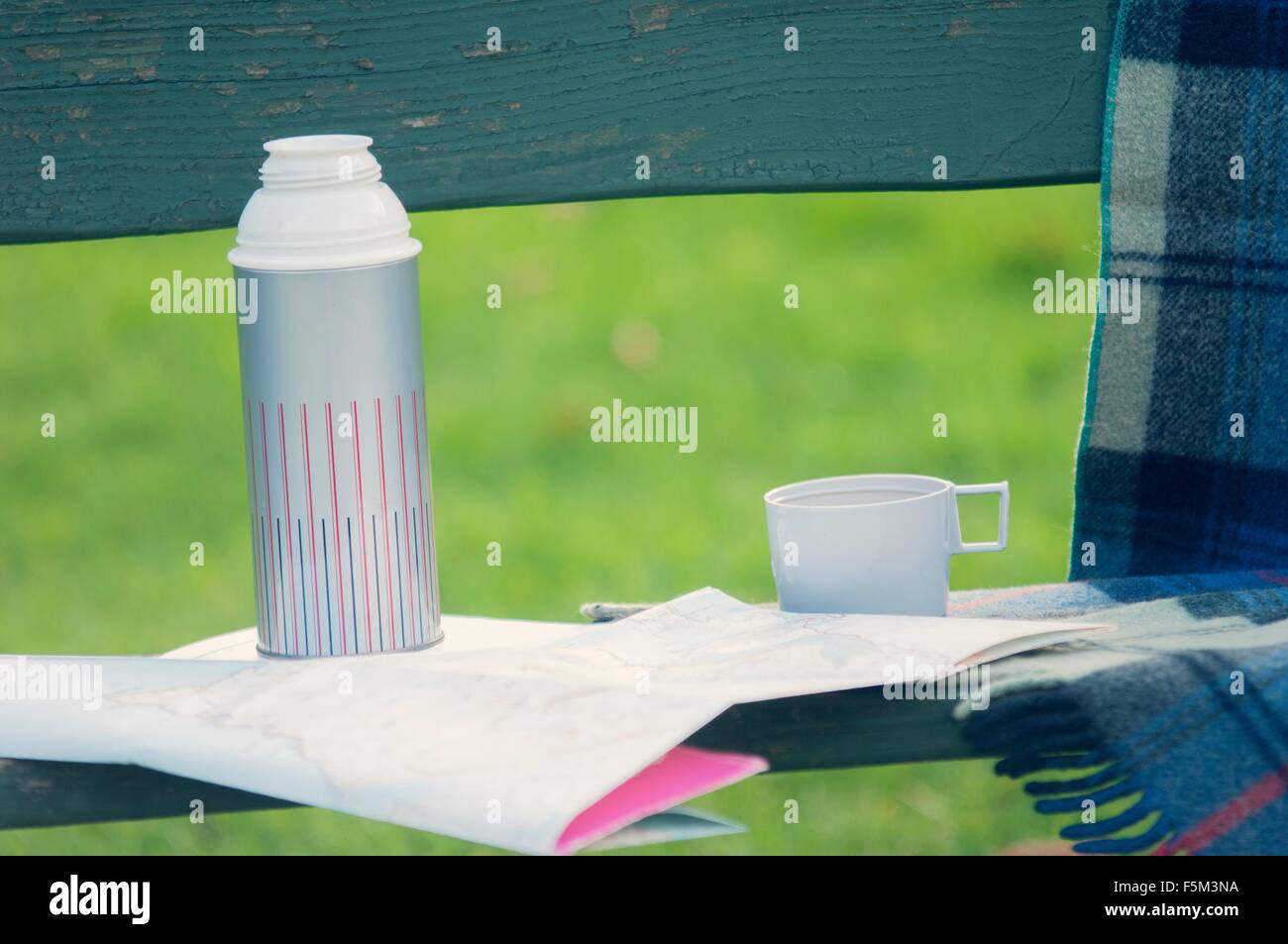 Getränke-Kolben und Faltplan auf Parkbank Stockfoto