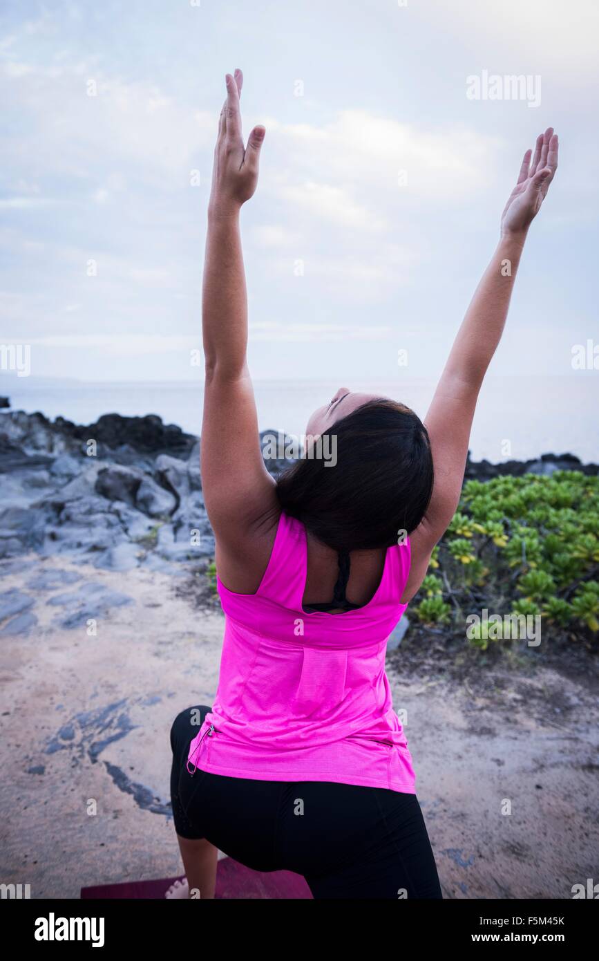 Frau am Küste praktizieren Yoga mit erhobenen Armen Stockfoto