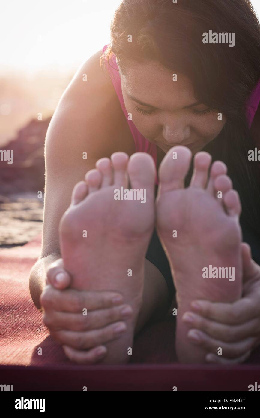 Nahaufnahme von Frau hält ihre Füße üben von Yoga bei Sonnenaufgang Stockfoto