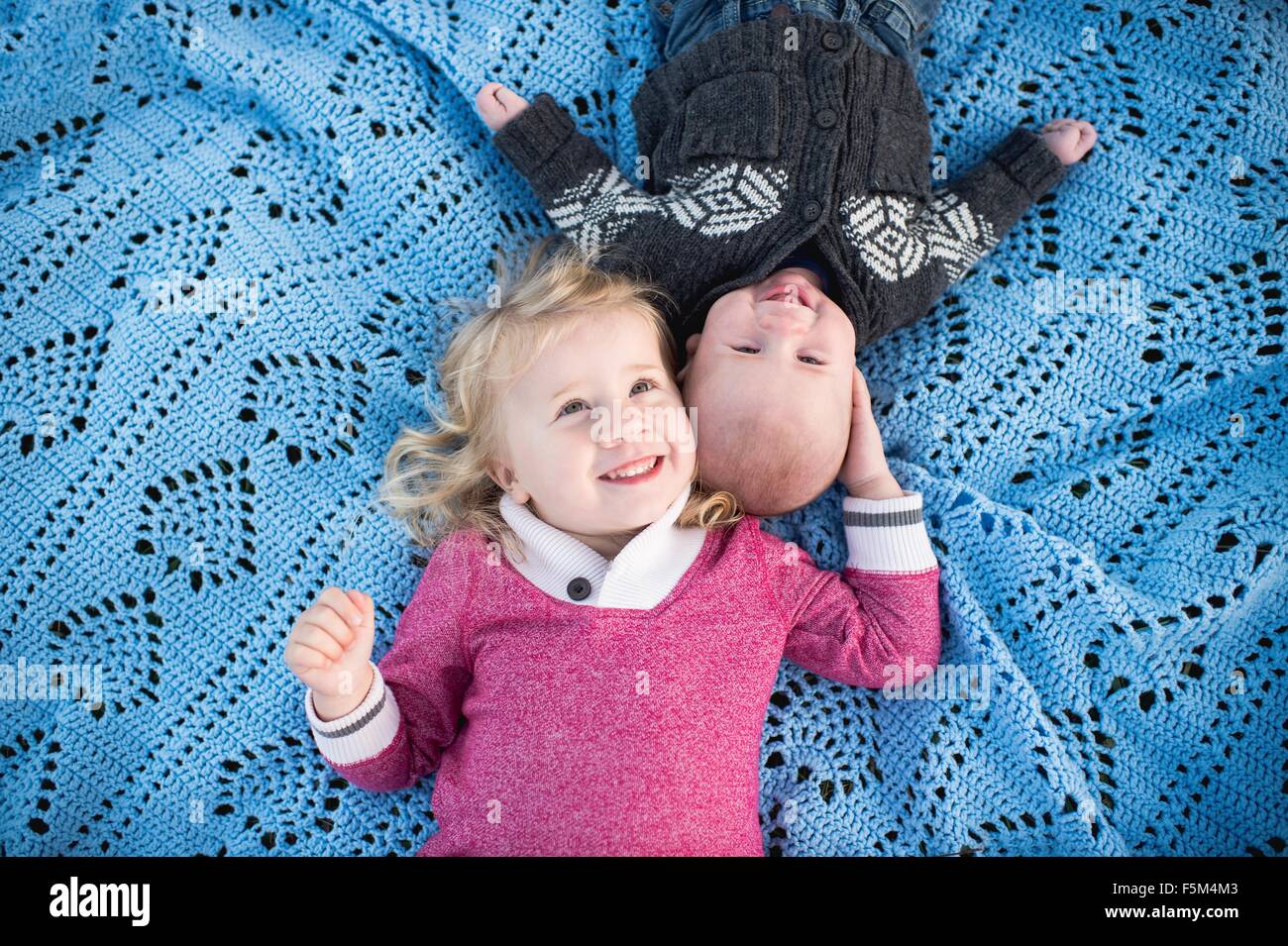 Obenliegende Porträt von Mädchen auf blauen Picknickdecke mit kleinen Bruder Stockfoto