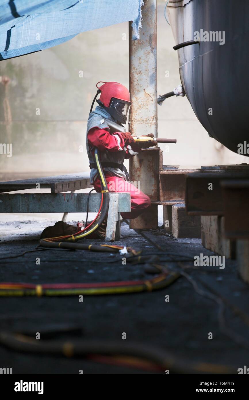 Arbeiter Sandstrahlen Bootsrumpf in Werft Stockfoto